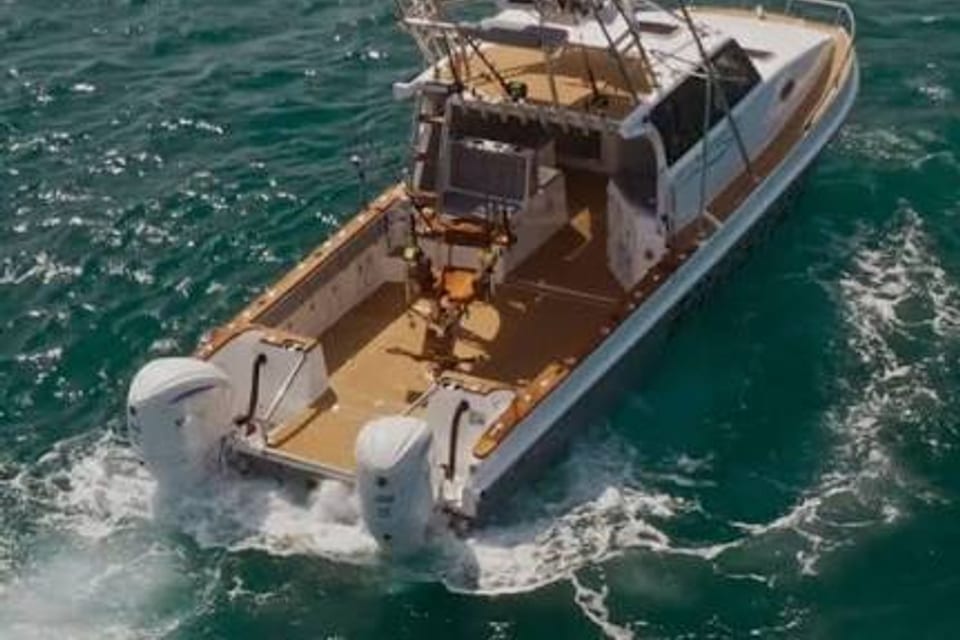 A twin-outboard sportfishing boat with outriggers, seen from above under way.