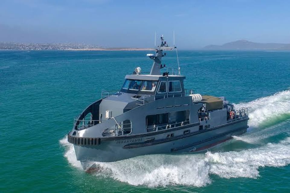 A grey commercial crew-carrier workboat at speed off the Cape coast.