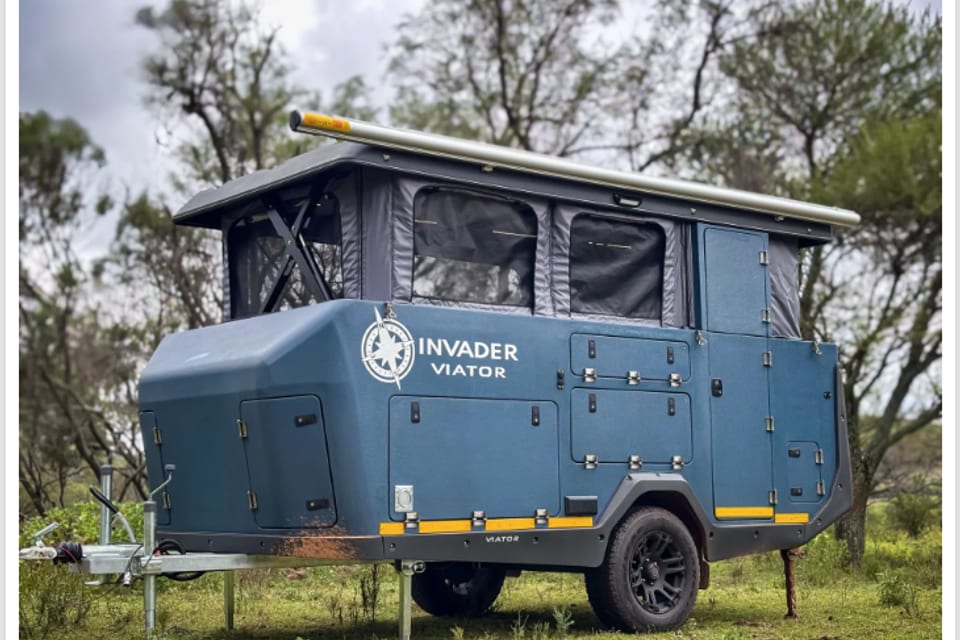 An Invader Viator off-road caravan with its pop-top roof raised, parked in the bush.