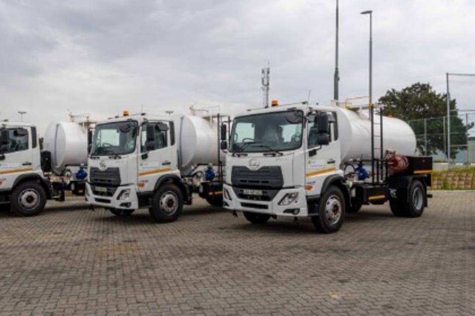 A fleet of white municipal water-tanker utility trucks lined up.